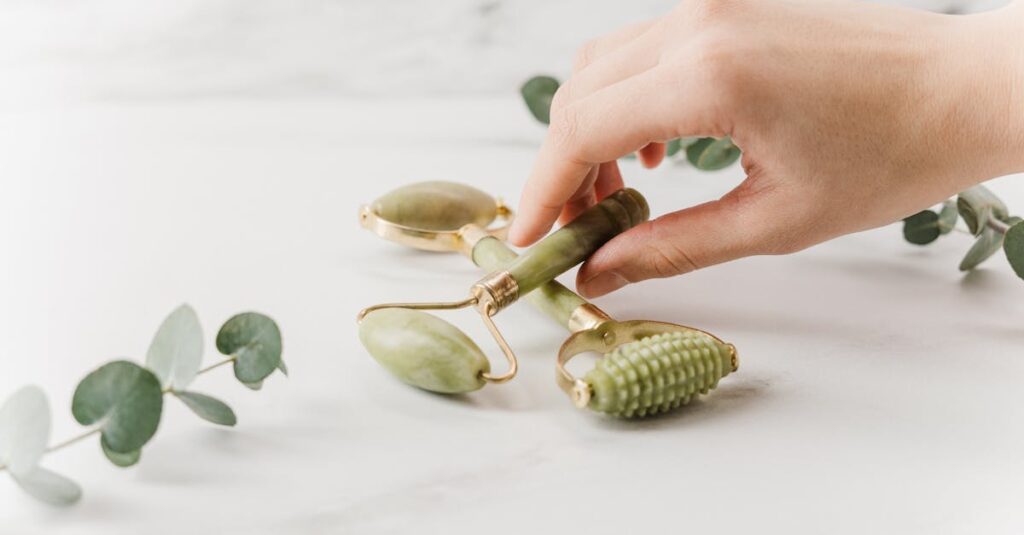 Close-up of a hand holding jade rollers on a marble surface for skincare and wellness.