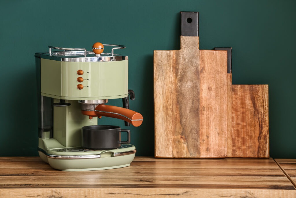 Modern coffee machine on kitchen counter near green wall