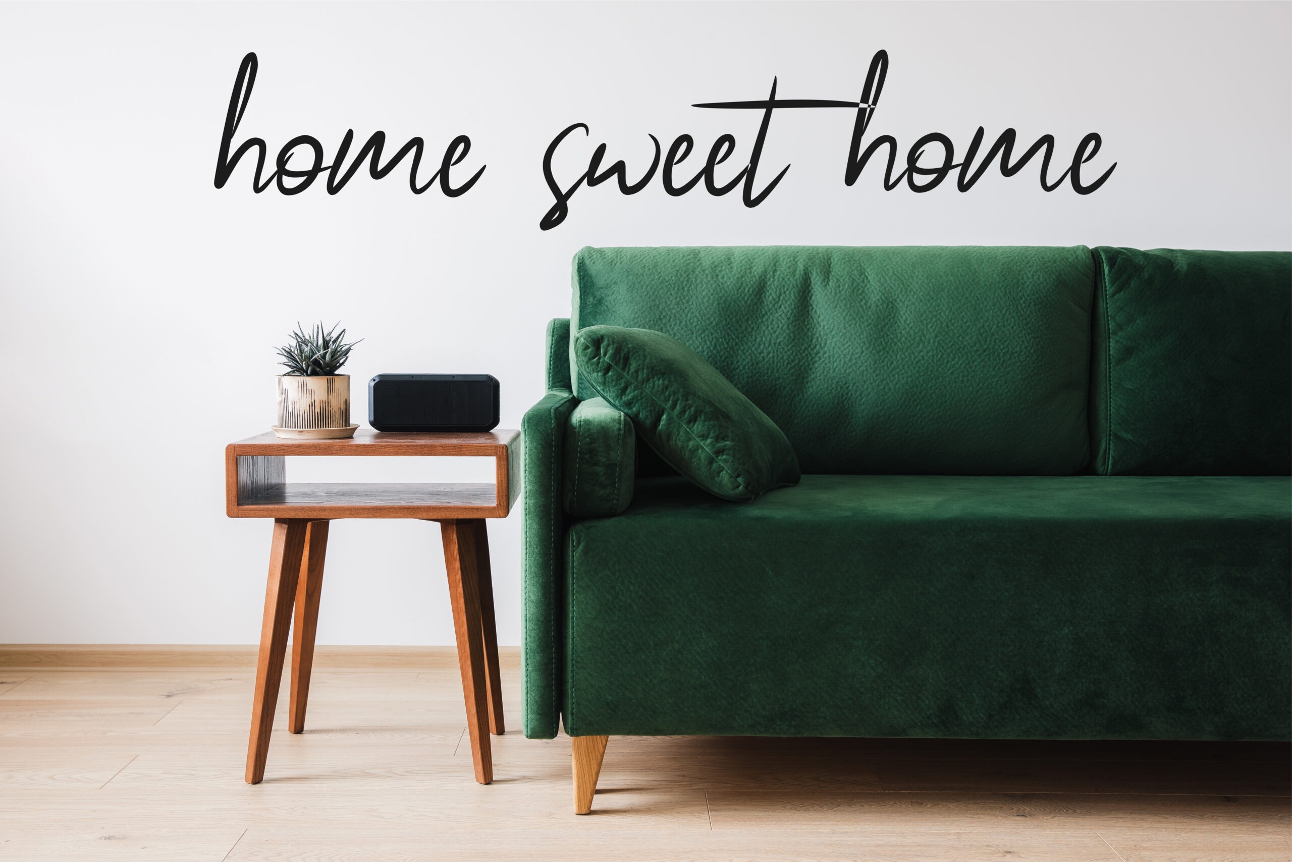 green sofa, pillow, wooden coffee table with plant and alarm clock near home sweet home lettering