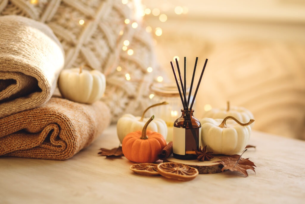 Affordable fall decor setup with pumpkins, blankets, lights, and oil diffuser