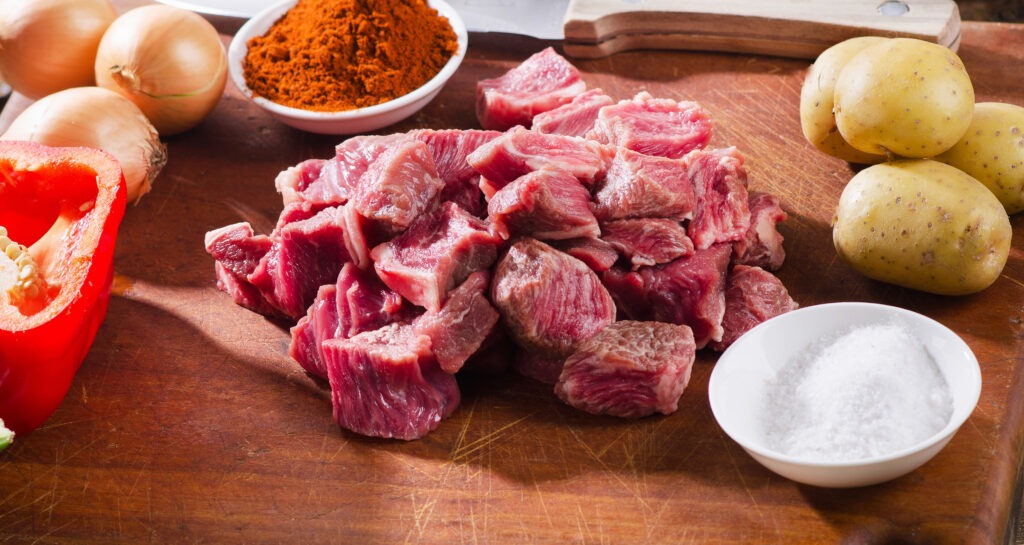 Ingredients for slow cooker beef stew on a rustic wooden table